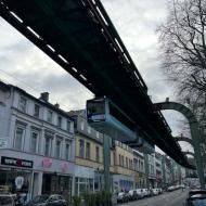 ein Wagen der Baureihe 14 schwebt durch Vohwinkel kurz hinter der Haltestelle Vohwinkel, die Oberleitung der O-Busse aus Solingen ist darunter erkennbar (01.02.2026) - 125 Jahre Wuppertaler Schwebebahn - Alltagssezenen